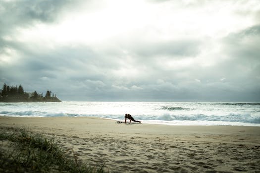 A surfer warming up on a sandy beach under cloudy skies along the Sunshine Coast, Australia.