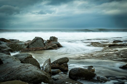 Tranquil scene of waves crashing on a rocky shore under an overcast sky, capturing natural beauty.