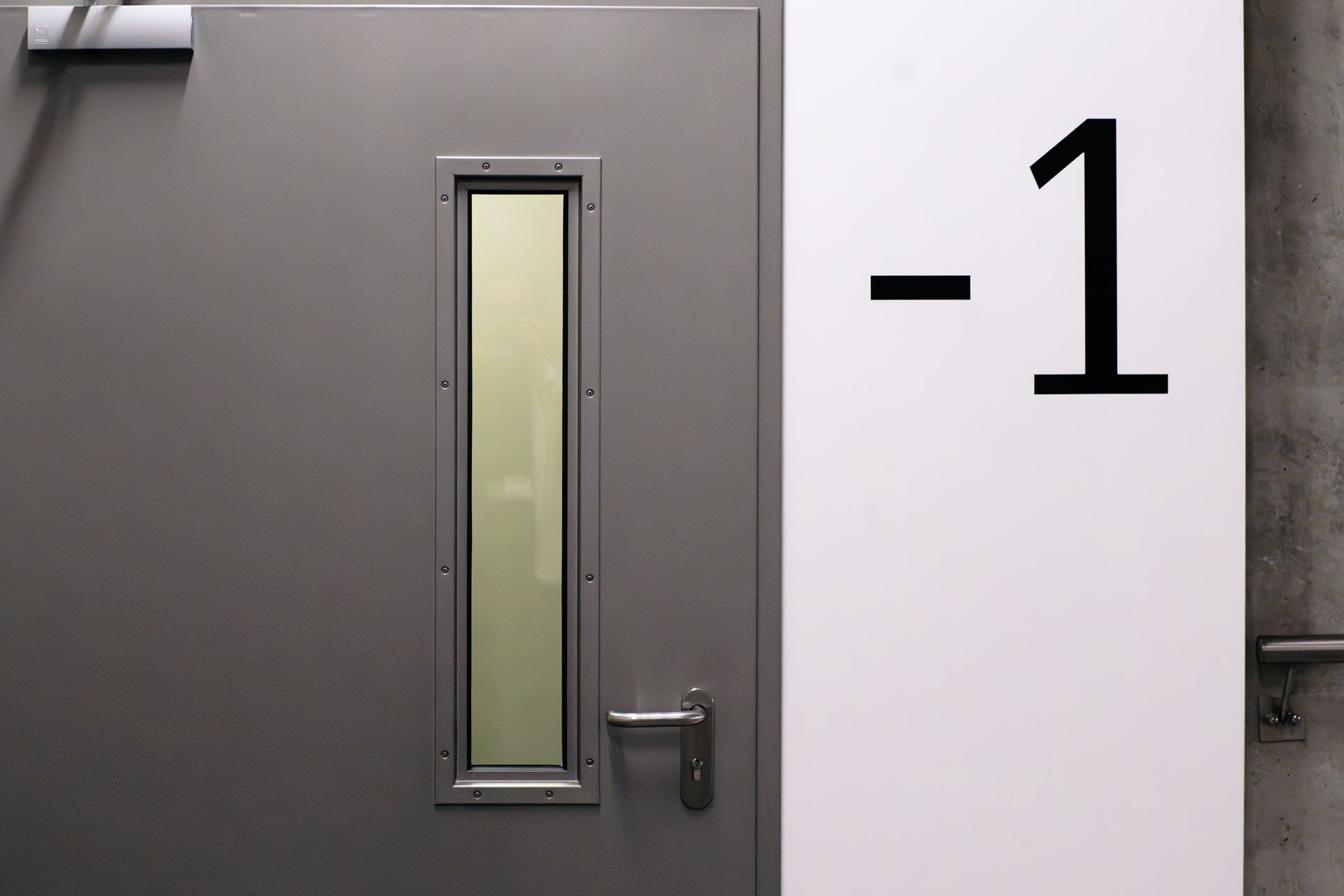 Minimalist scene featuring an industrial basement door marked with a '-1' emergency exit sign.