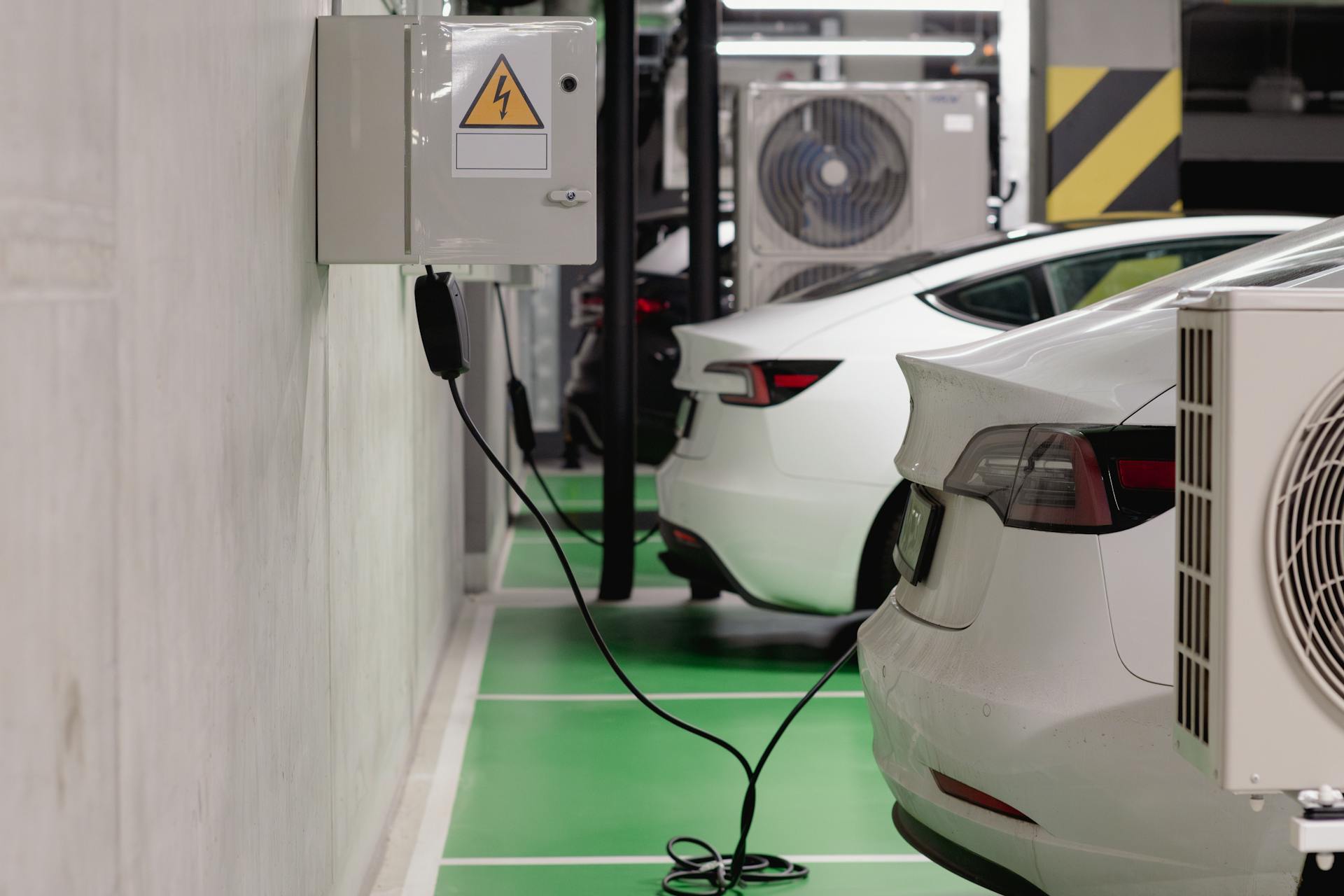 Electric vehicles charging at an indoor station in a modern underground garage.