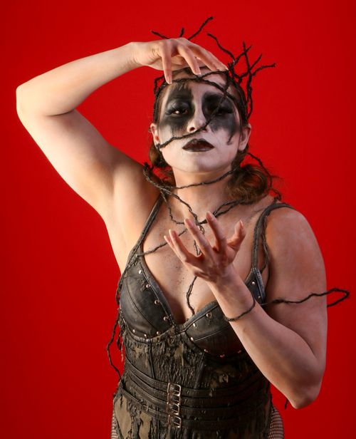 Free Gothic woman with creative makeup and costume on a red background posing dramatically. Stock Photo