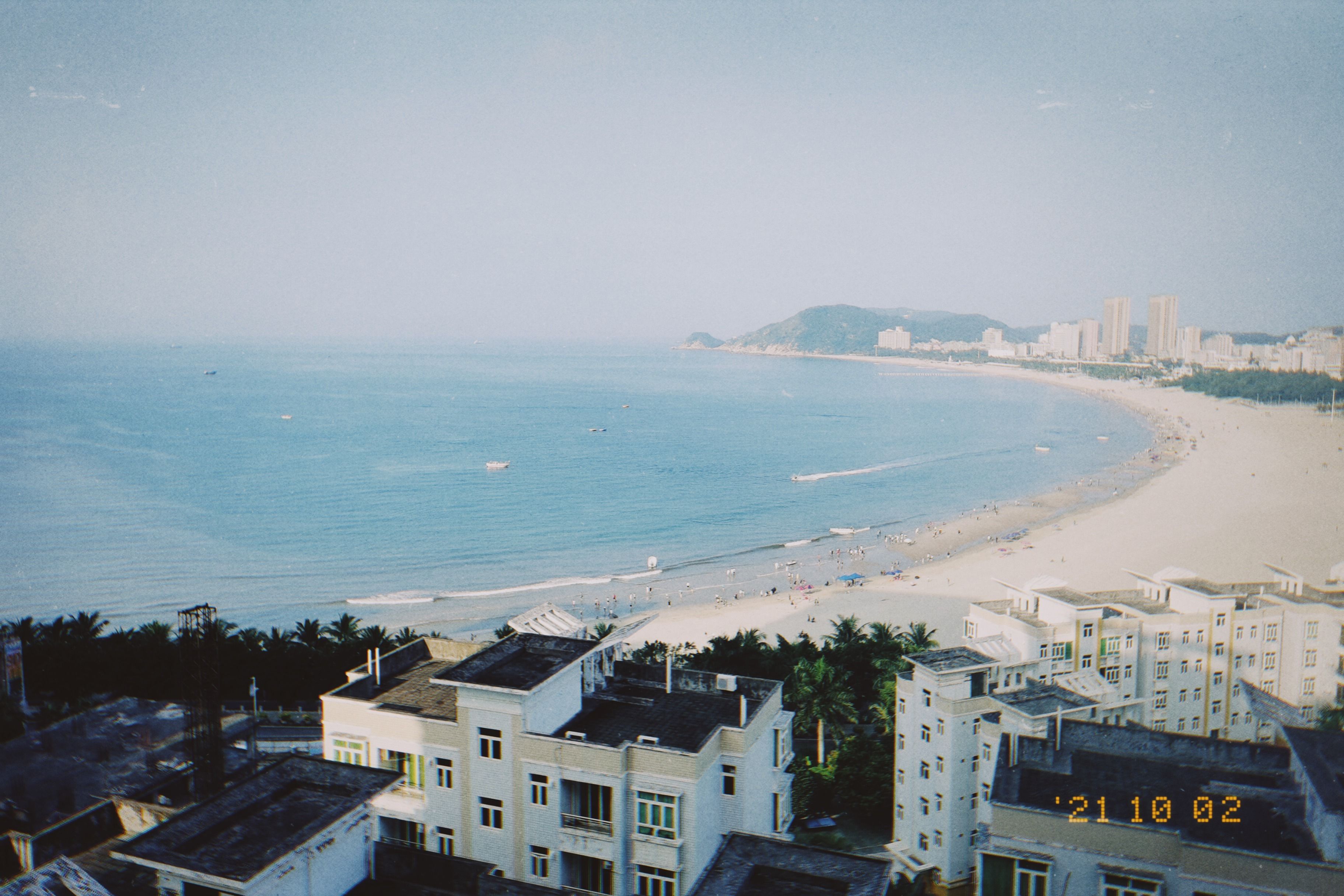 Scenic aerial view of a coastal city with sandy beach and clear blue water, ideal for travel inspiration.
