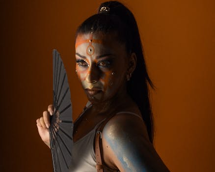 A striking portrait of a person in artistic Halloween makeup with a bold orange backdrop.