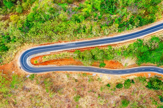 Stunning aerial shot of a winding road amidst lush greenery in West Java, Indonesia.