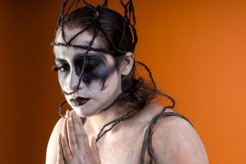 Free Dramatic Halloween-themed portrait with dark and artistic makeup on an orange background. Stock Photo