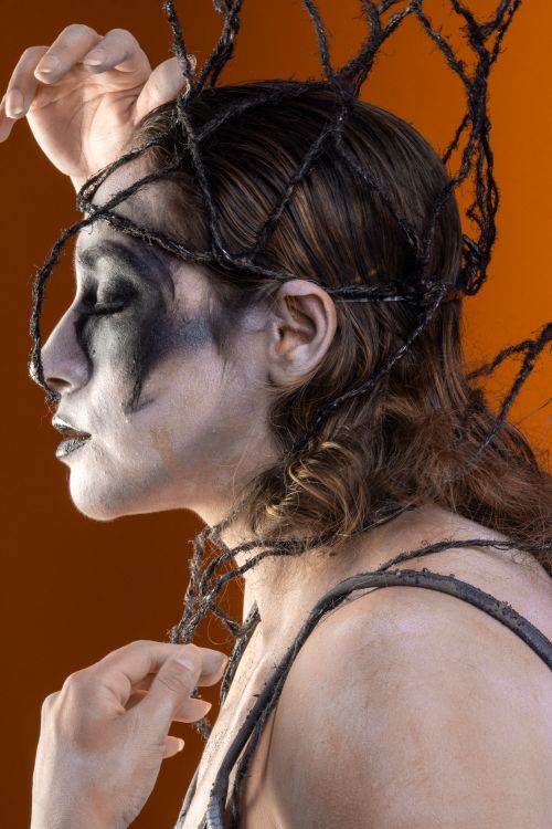 Free Side profile of a person with creative Halloween makeup and web-like design on an orange background. Stock Photo