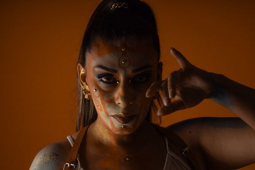 Free Striking portrait featuring creative makeup art with an orange backdrop. Stock Photo