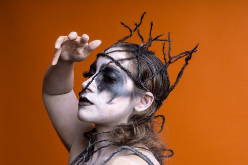 Free Dramatic artistic makeup against a vivid orange backdrop for Halloween. Stock Photo