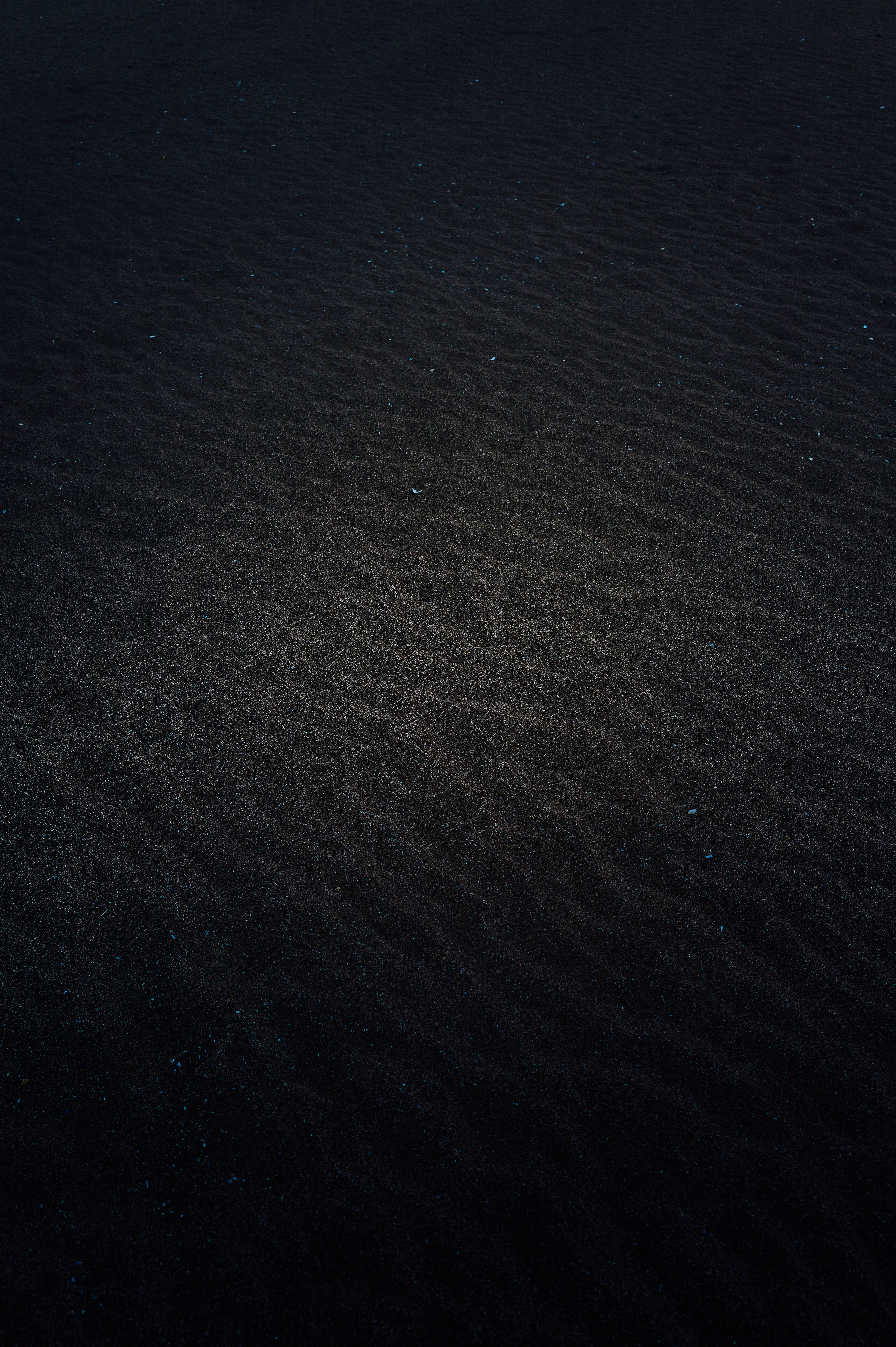 Fotomural Una foto minimalista de arena oscura con luz suave y textura, evocando una atmósfera misteriosa y melancólica.