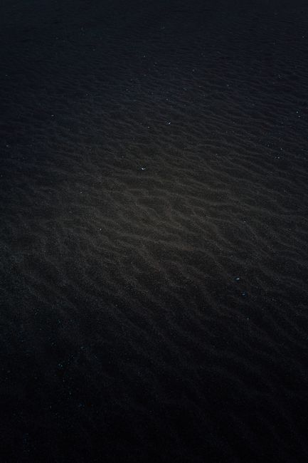 Fotomural Una foto minimalista de arena oscura con luz suave y textura, evocando una atmósfera misteriosa y melancólica.
