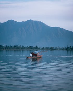 A peaceful scene of a boat on a calm lake with majestic mountains in the background.