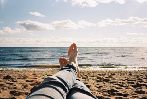 A person relaxing on a sandy beach near the ocean with a clear blue sky.