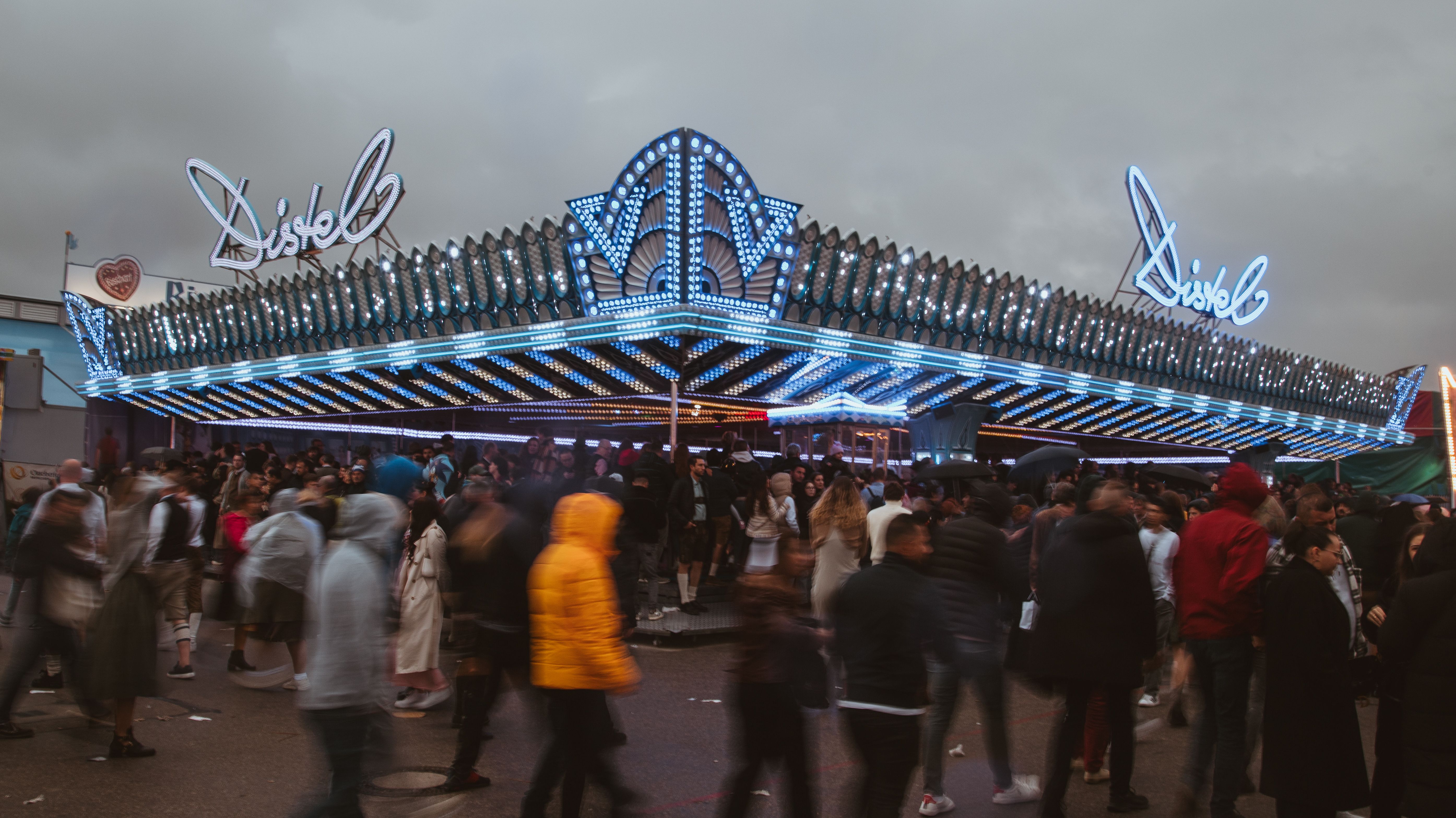 People enjoying a bustling carnival scene at night under dazzling neon lights.