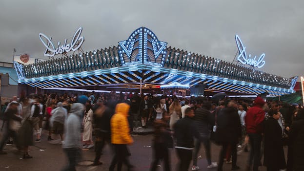People enjoying a bustling carnival scene at night under dazzling neon lights.