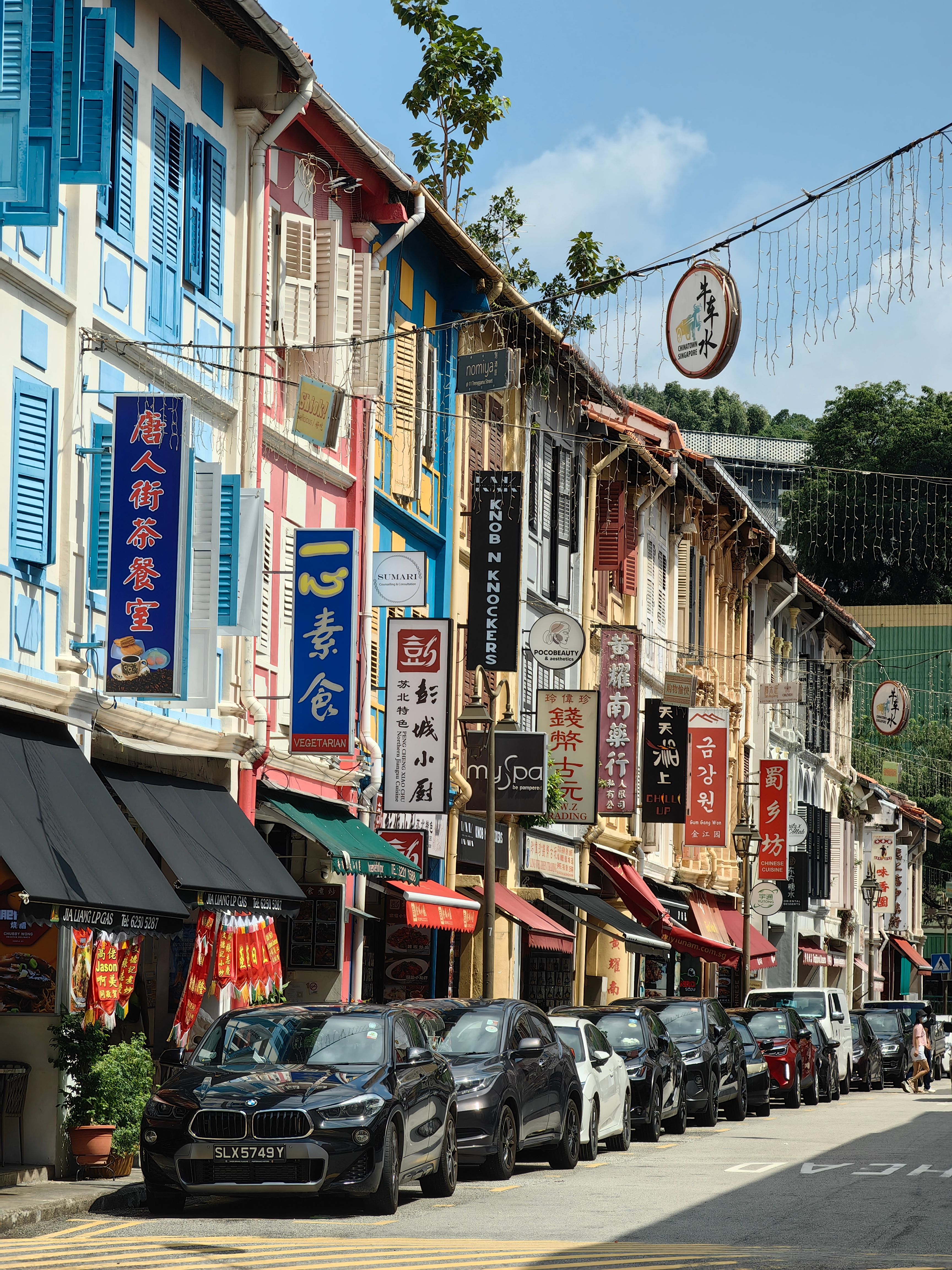 Colorful heritage buildings line a bustling street in Singapore's Chinatown.