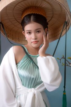 Beautiful Vietnamese woman in traditional dress poses gracefully with a conical hat.