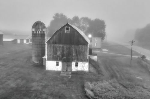 Free A misty black and white aerial view of a rustic barn on a rural farm. Stock Photo