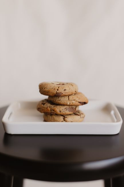 A stack of golden-brown chocolate chip cookies with crisp edges, melted chocolate chips visible, cooling on a wire rack.