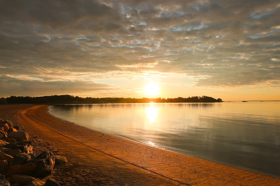 Tranquil sunrise over serene waters and sandy beach at Cove Island Park, Stamford.