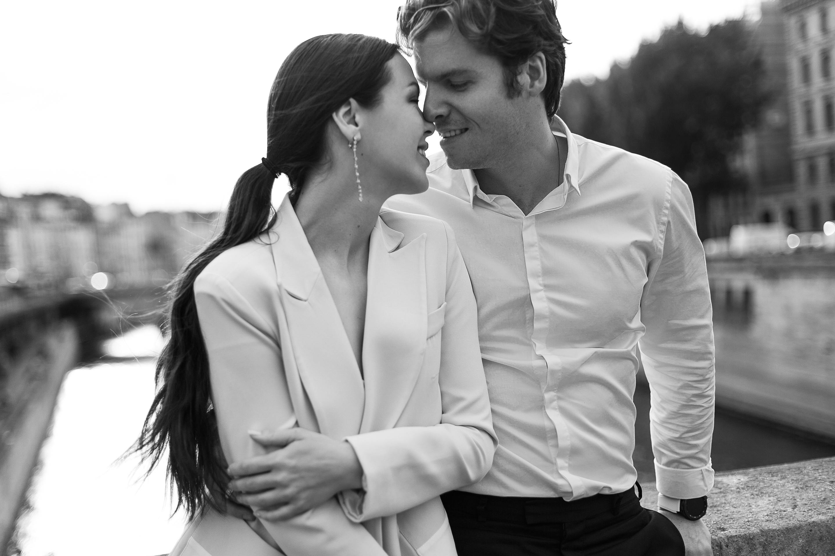 A romantic moment captures a couple in love by the river in black and white.