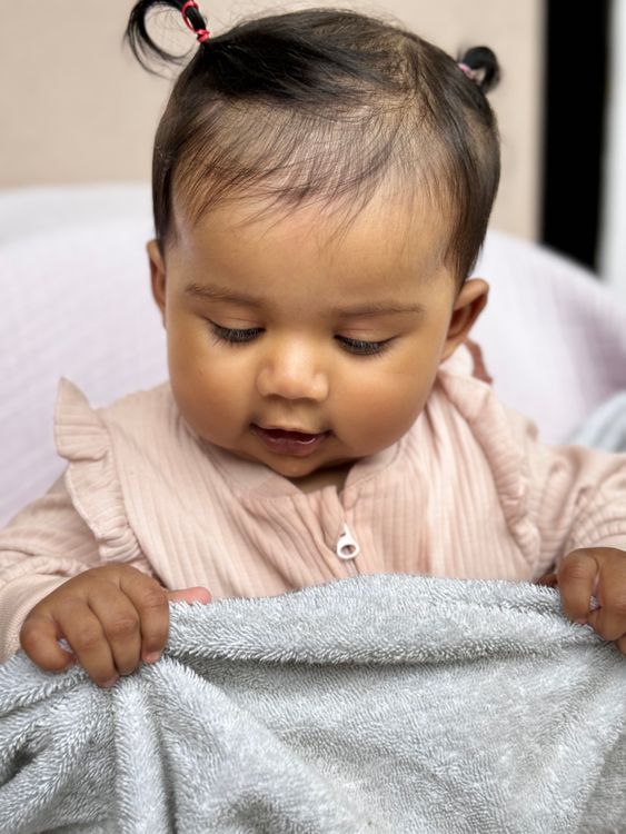 Adorable Baby in Pink Outfit Looking at Blanket · Free Stock Photo