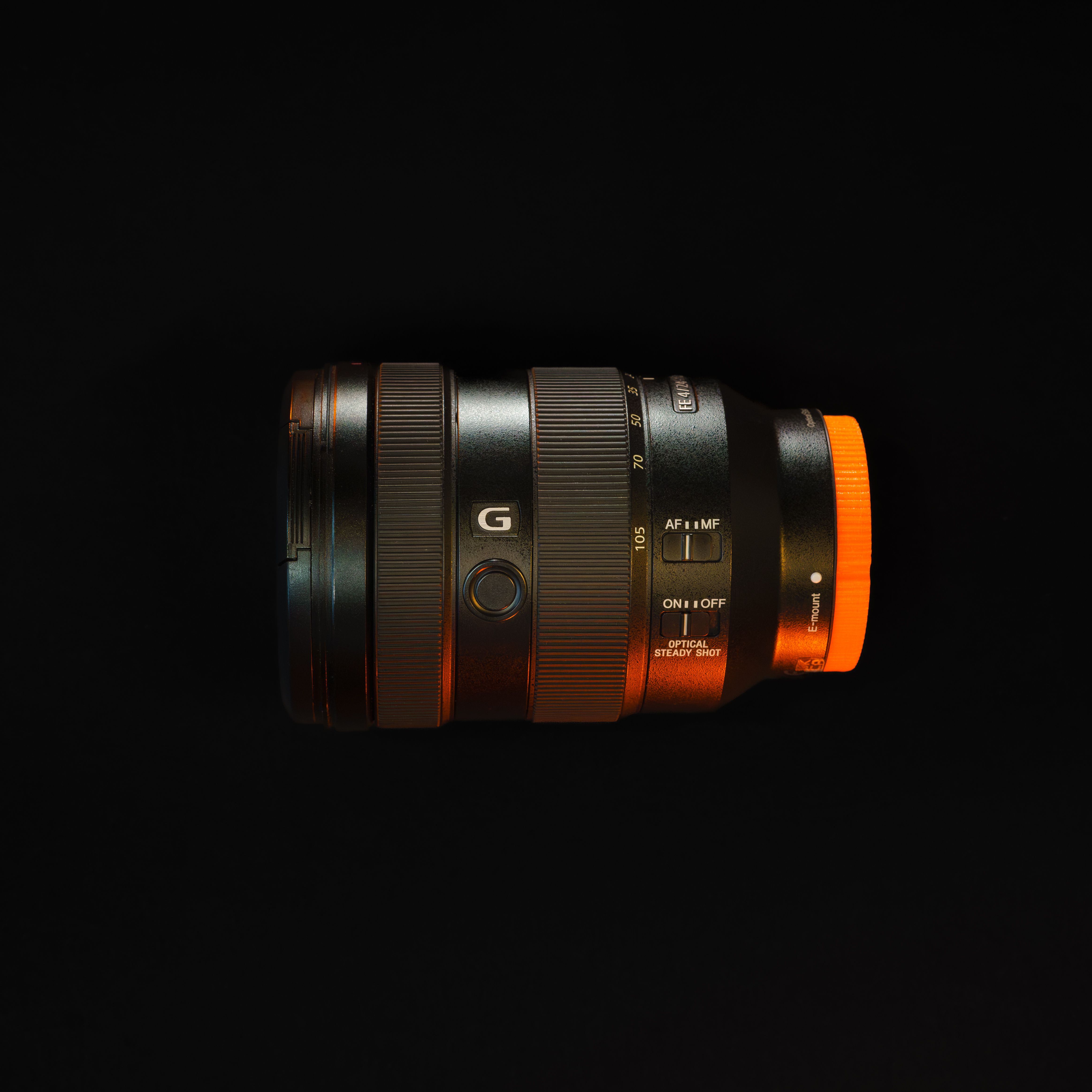 Detailed shot of a professional camera lens with black background, showcasing design and features.