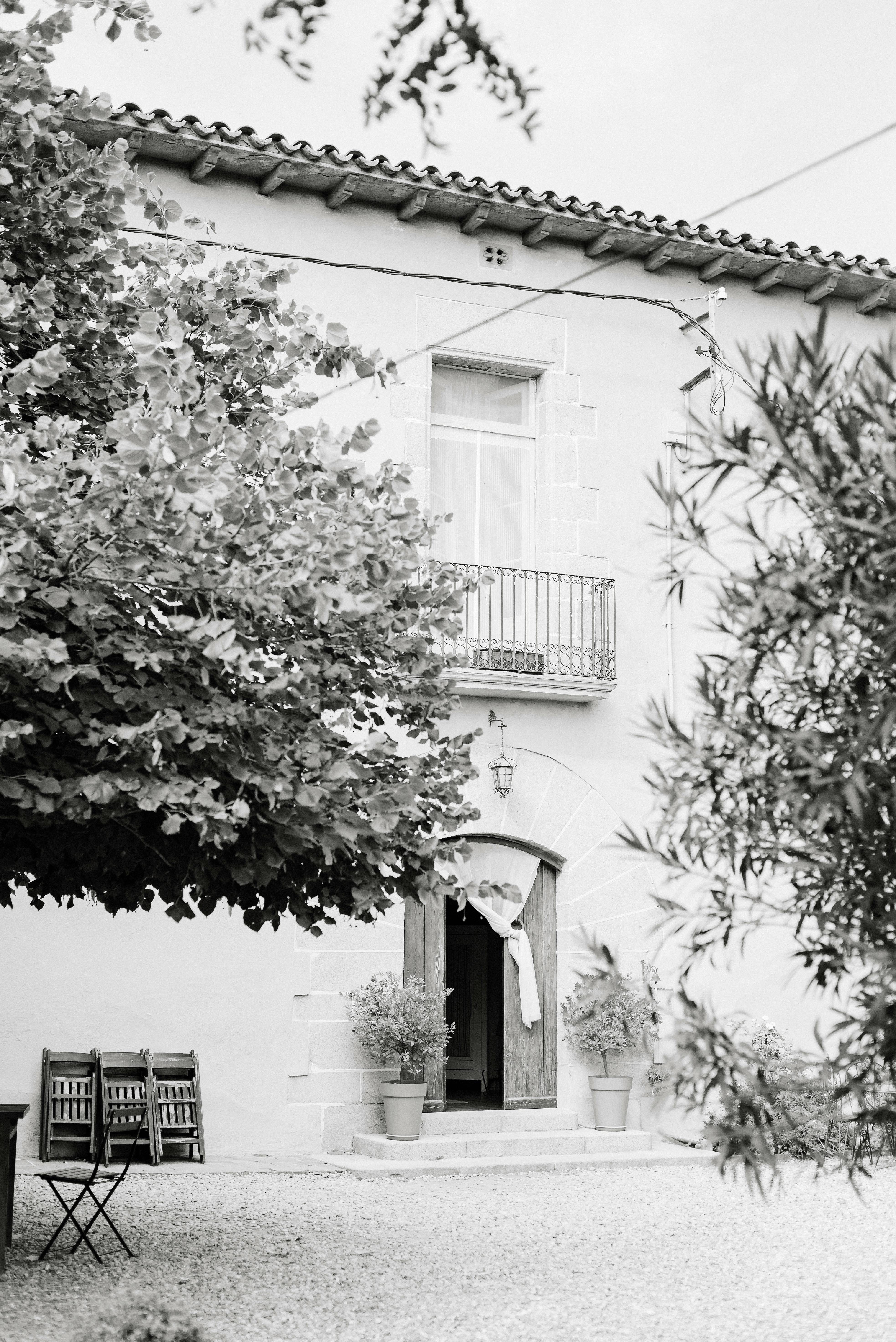 Rustic house exterior with trees and balcony in monochrome tone.