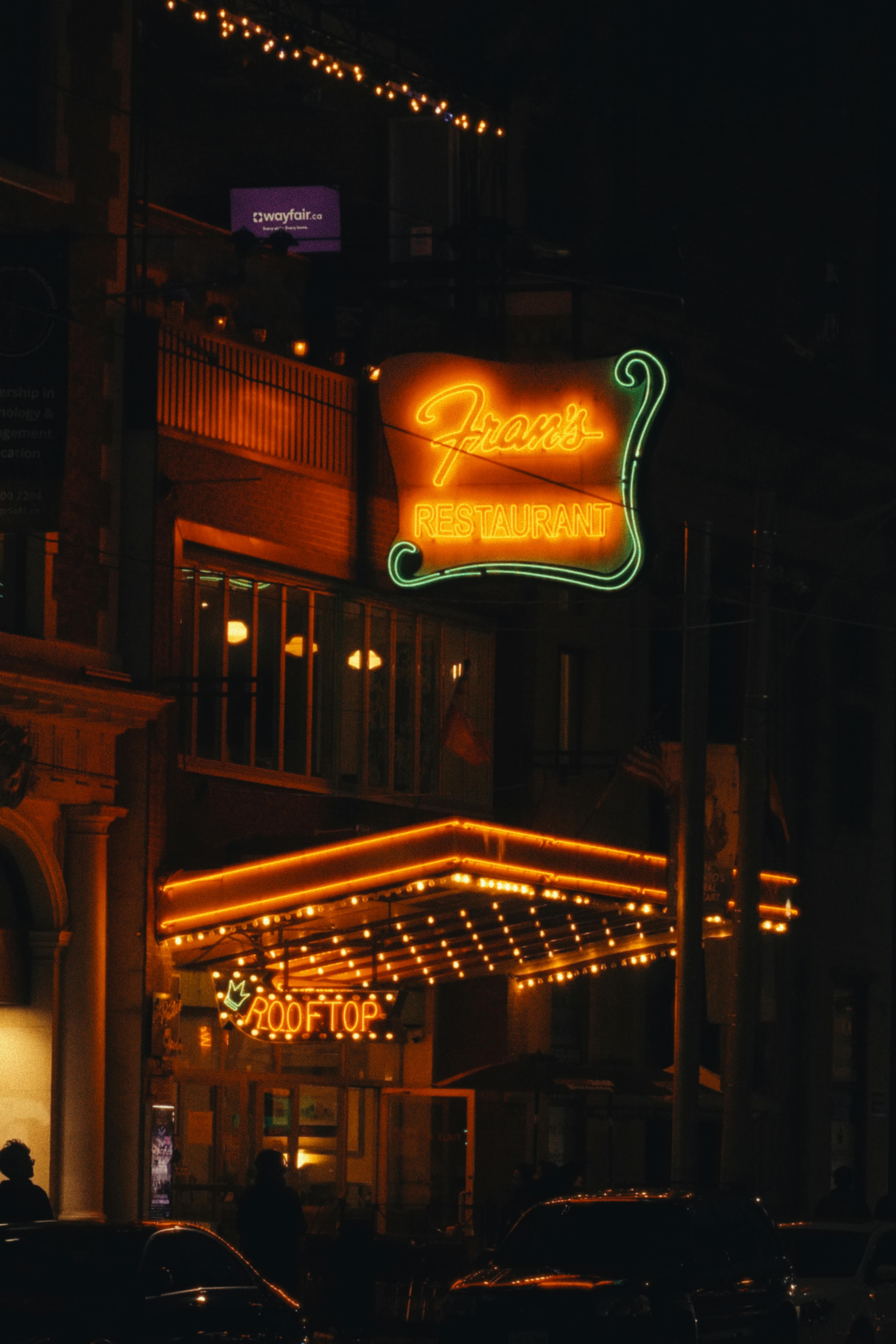 Illuminated facade of Fran's Restaurant with vibrant neon signs and a cozy evening vibe.