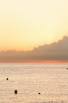 Capture of a serene sunrise over the sea in Barcelona, casting a warm, golden hue across the calm waters.