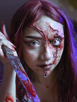 Spooky portrait featuring woman with intense Halloween makeup and a knife.