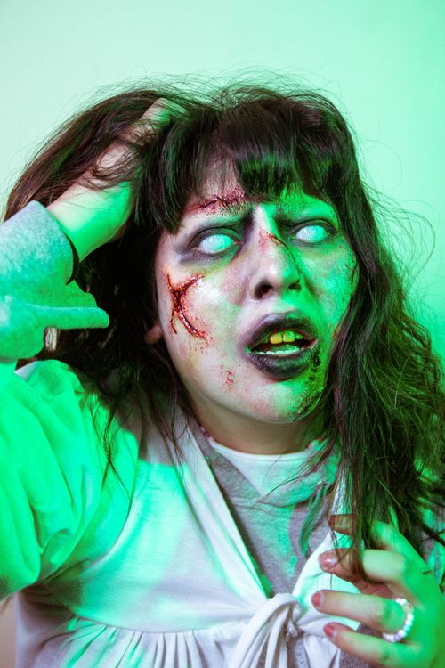 Free Scary zombie-themed portrait with glowing eyes and special effects makeup for Halloween. Stock Photo