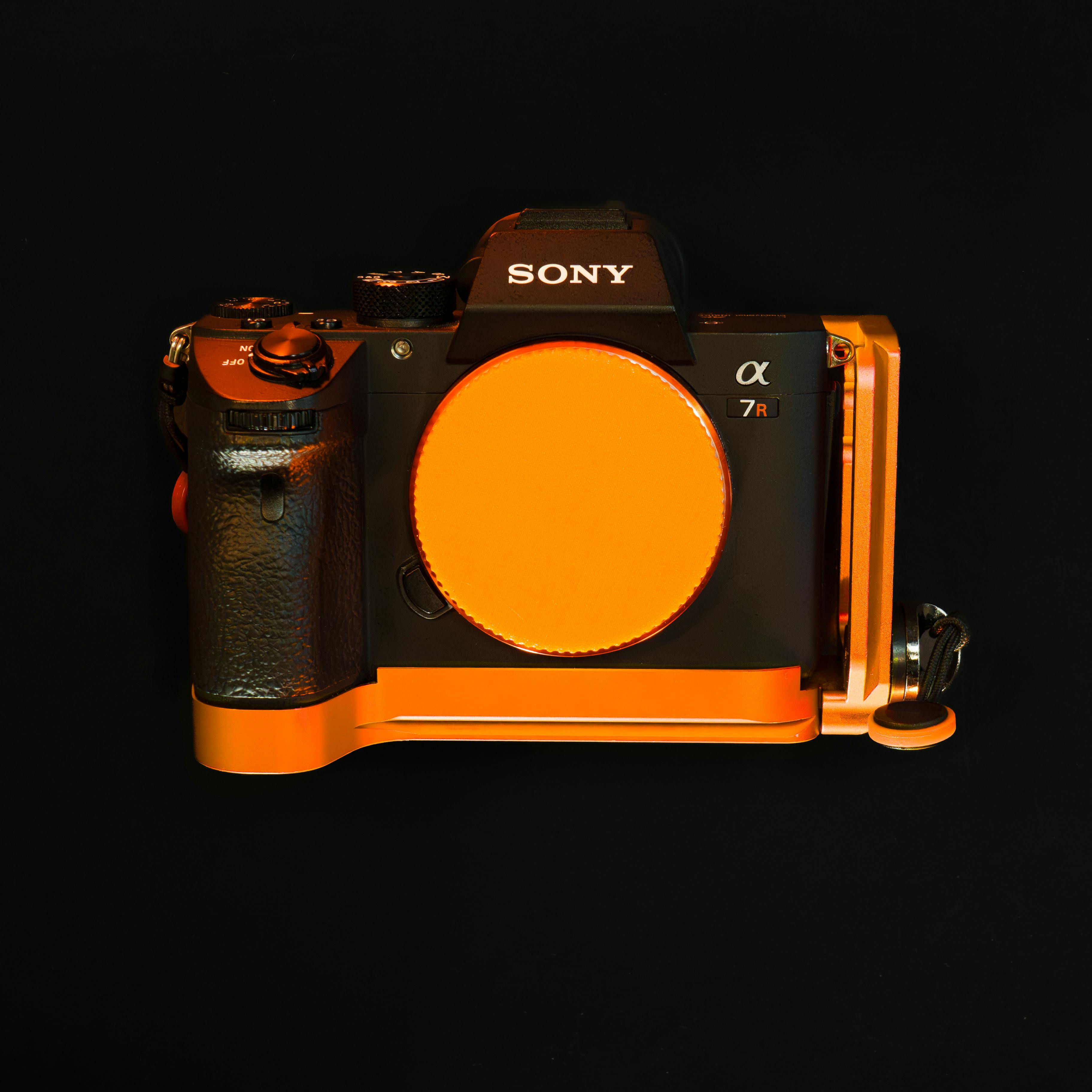 Detailed view of a professional camera with an orange case against a black background. Perfect for photography enthusiasts.