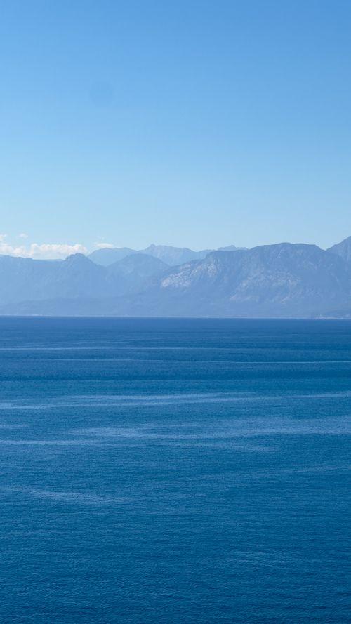 Free Tranquil blue ocean stretches to distant mountains under a clear sky. Stock Photo