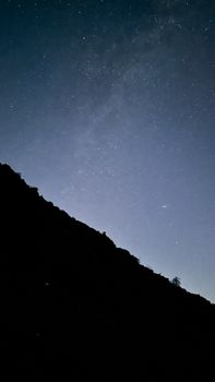 Night sky filled with stars above a silhouetted hillside.