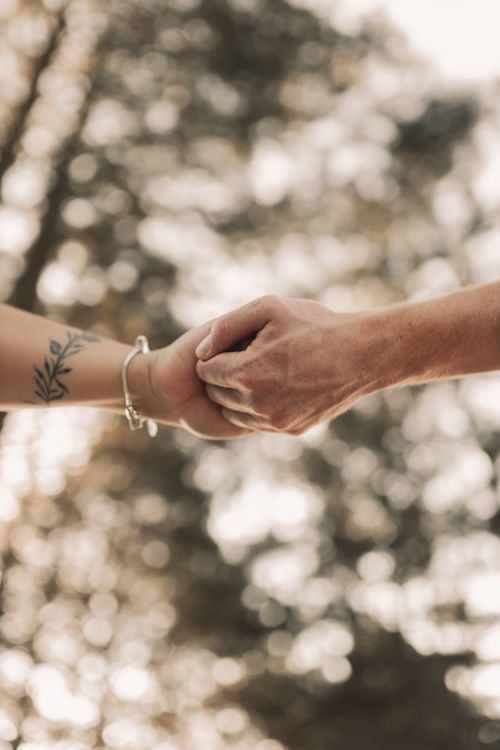 Free Close-up of two hands holding against a blurred natural background. Stock Photo