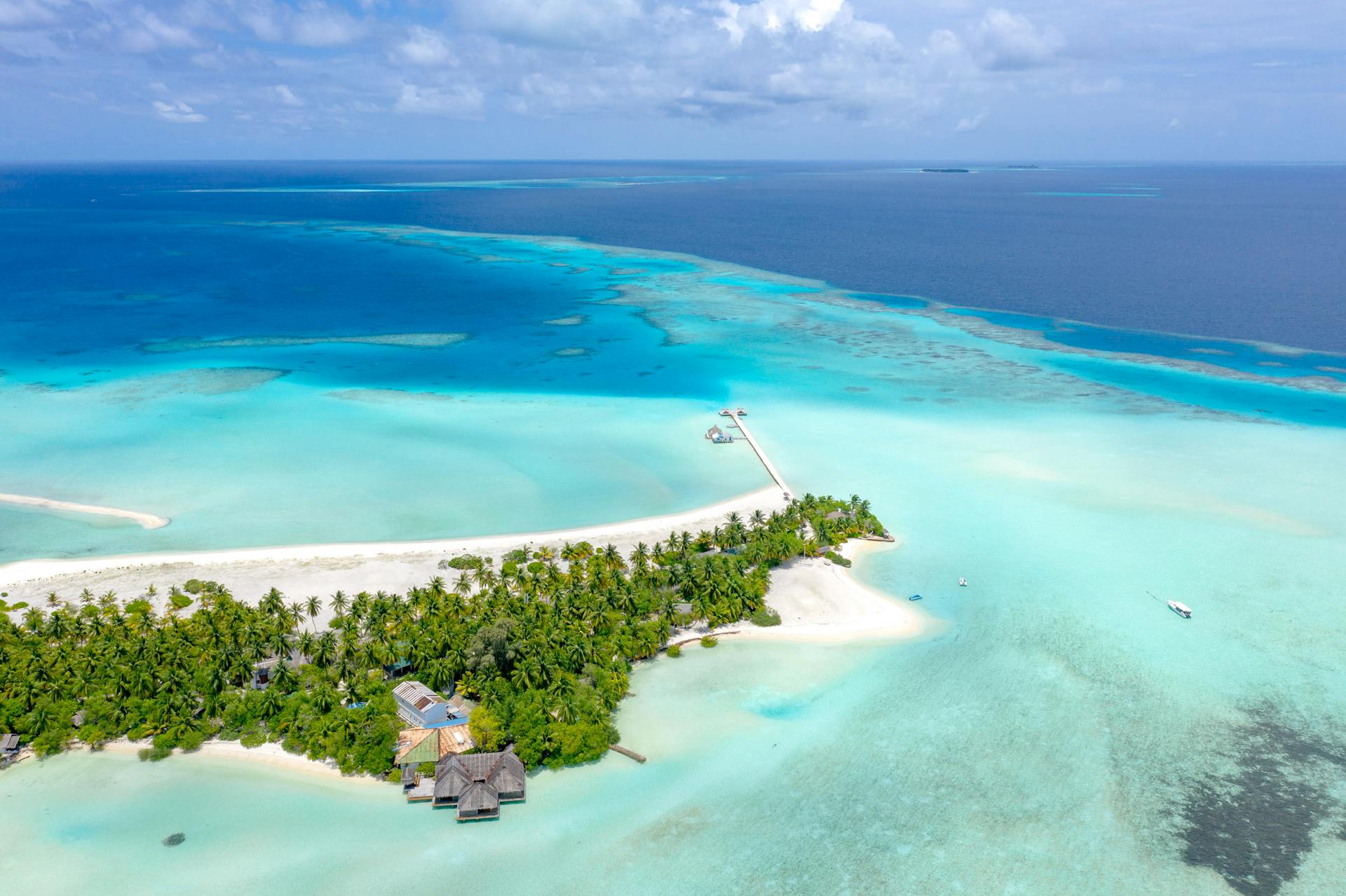 Aerial view of a tropical island with turquoise waters and white sand beaches in the Maldives.