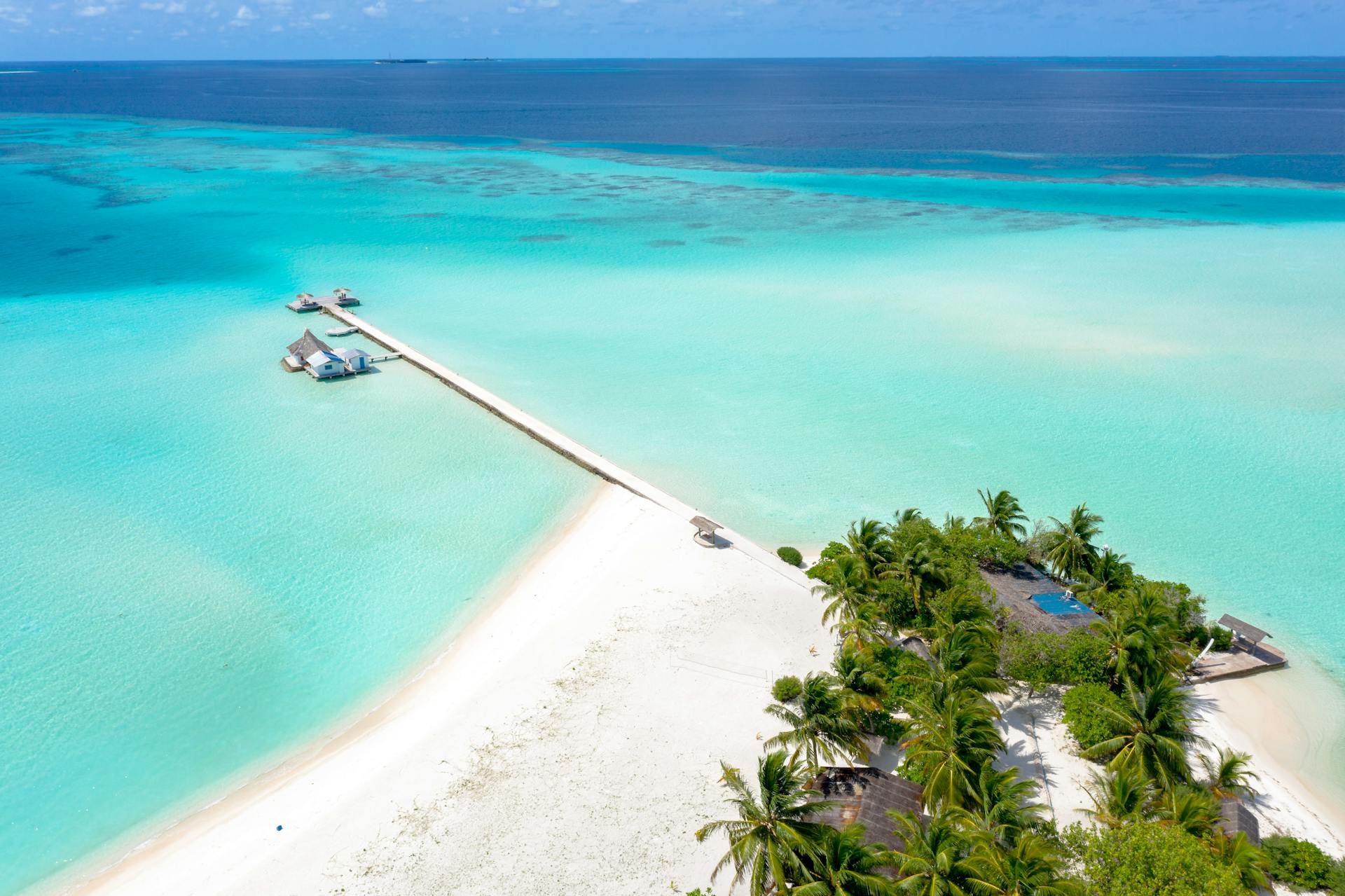 A serene aerial view of a private island in the Maldives with turquoise waters and white sandy beaches.