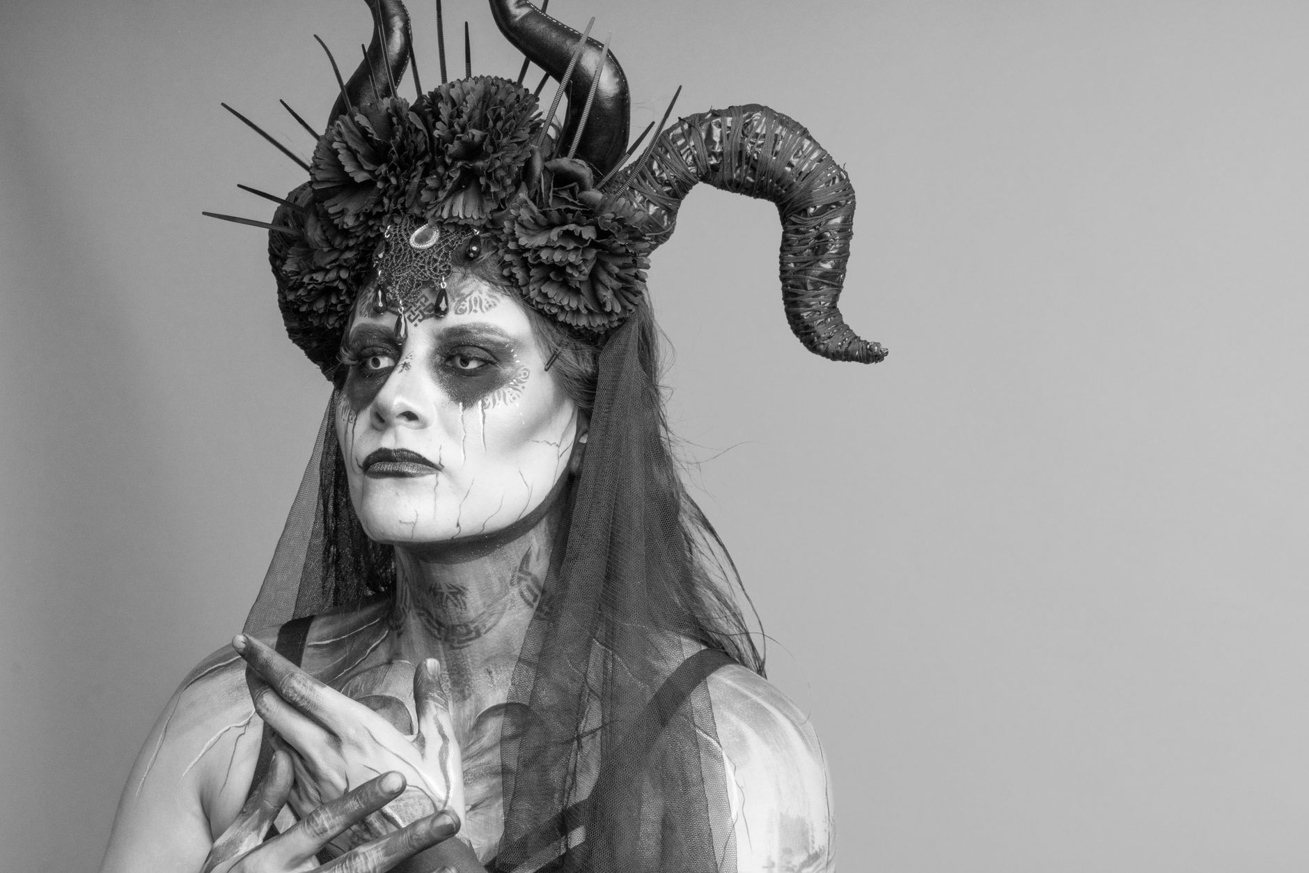 A black and white portrait featuring artistic makeup and elaborate headgear with horns.