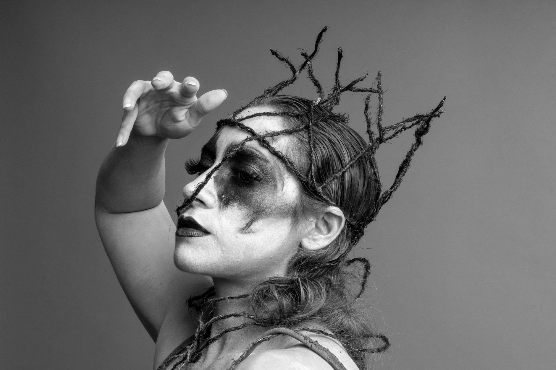 Striking black and white portrait featuring elaborate artistic makeup and creative headpiece.