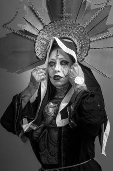 Artistic black and white portrait of a woman with creative makeup and headpiece.