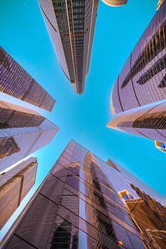 Dramatic view of Moscow City skyscrapers reaching towards a clear blue sky.