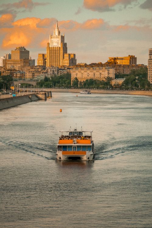 Free A picturesque view of the Moscow River with a ferry boat and cityscape at sunset. Stock Photo