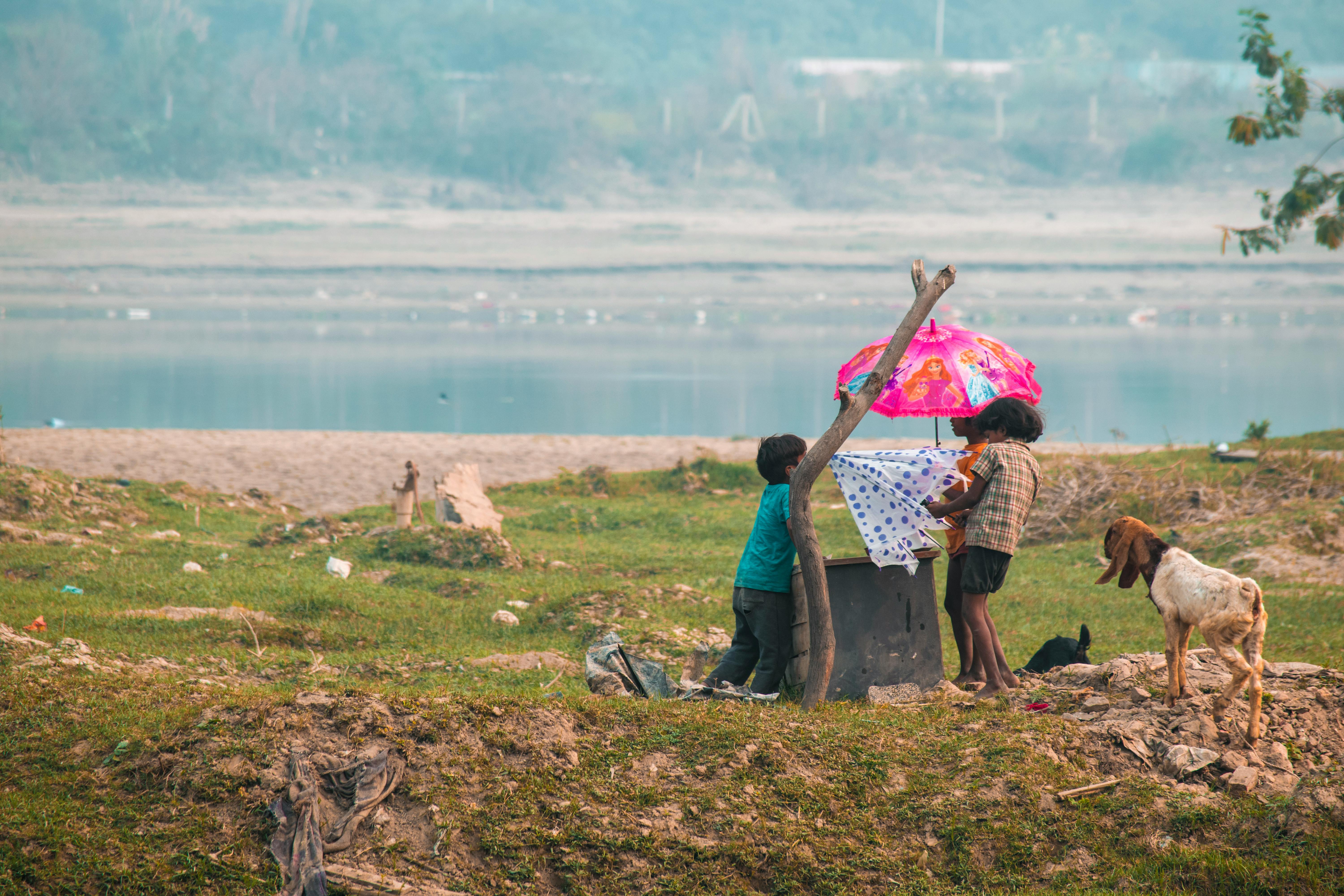 children playing by riverside with colorful umbrella