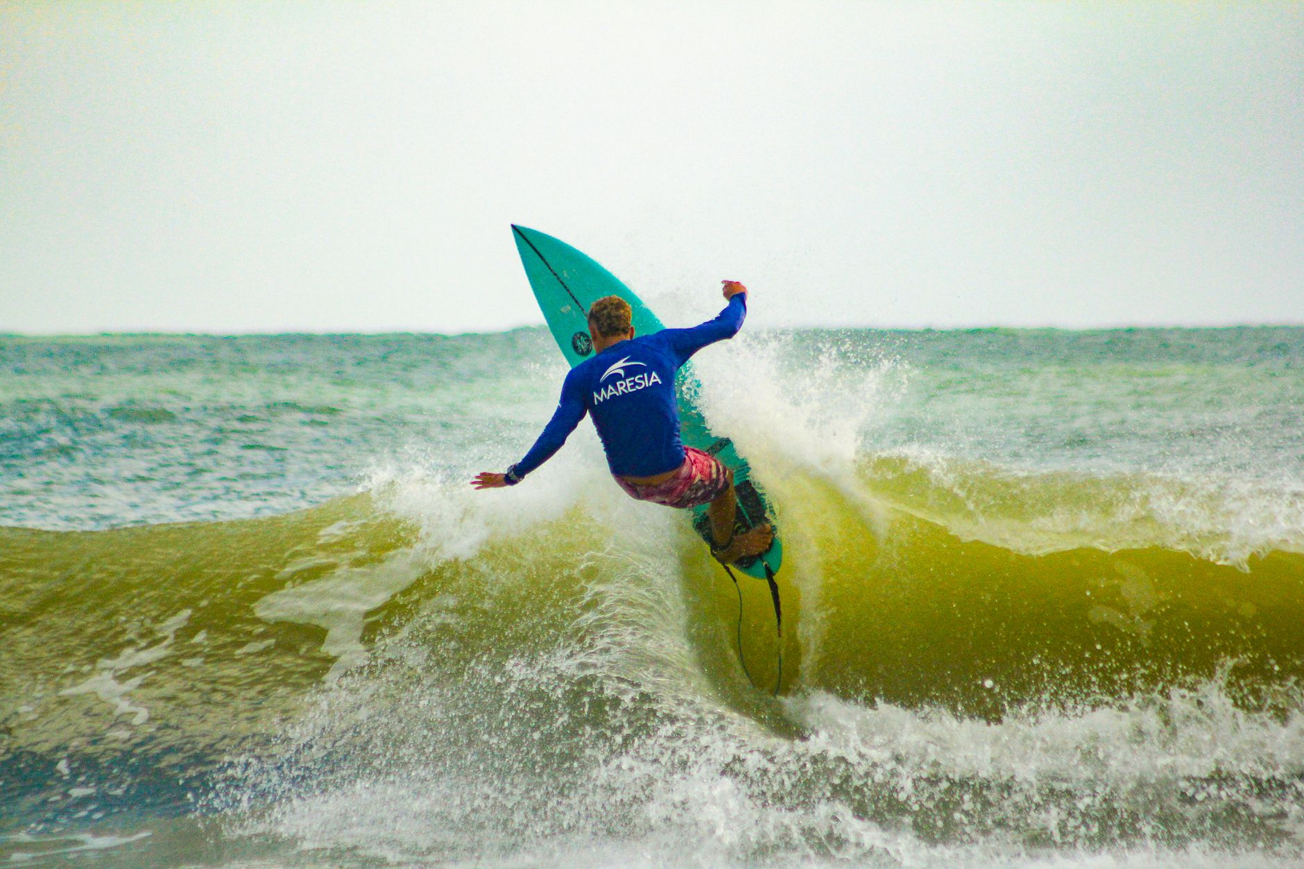 A surfer rides a powerful wave showcasing skill and energy in bright conditions.