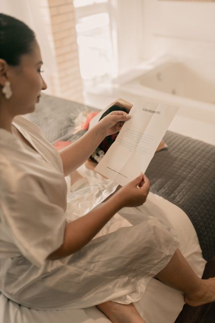 Woman in a robe reading a letter in a softly lit, cozy bedroom
