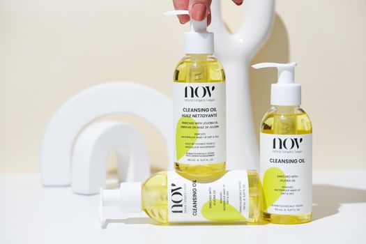 Natural cleansing oil bottles arranged with modern art objects in bright lighting.