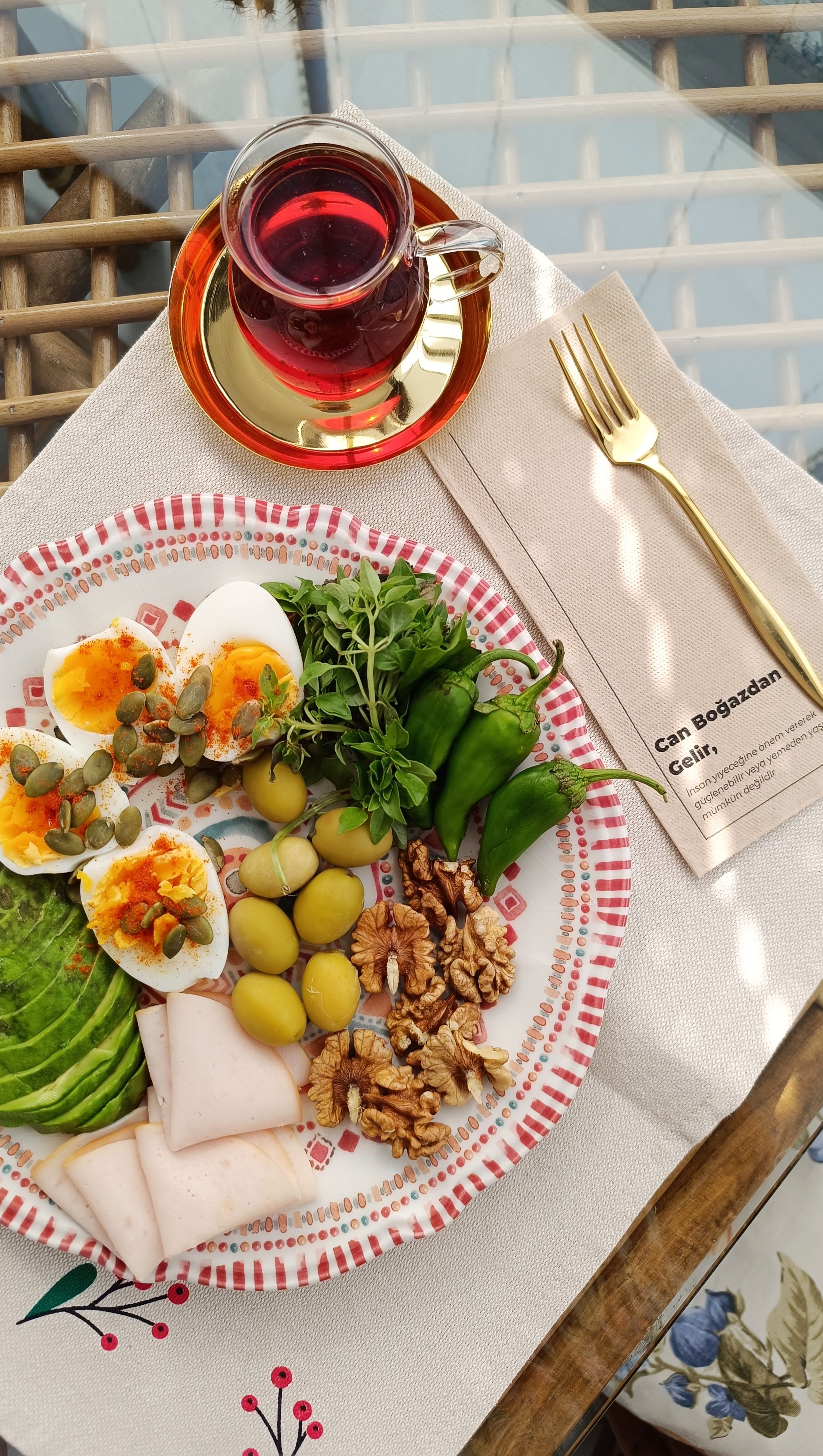 Colorful breakfast spread with tea, eggs, veggies, and nuts on a sunny table.