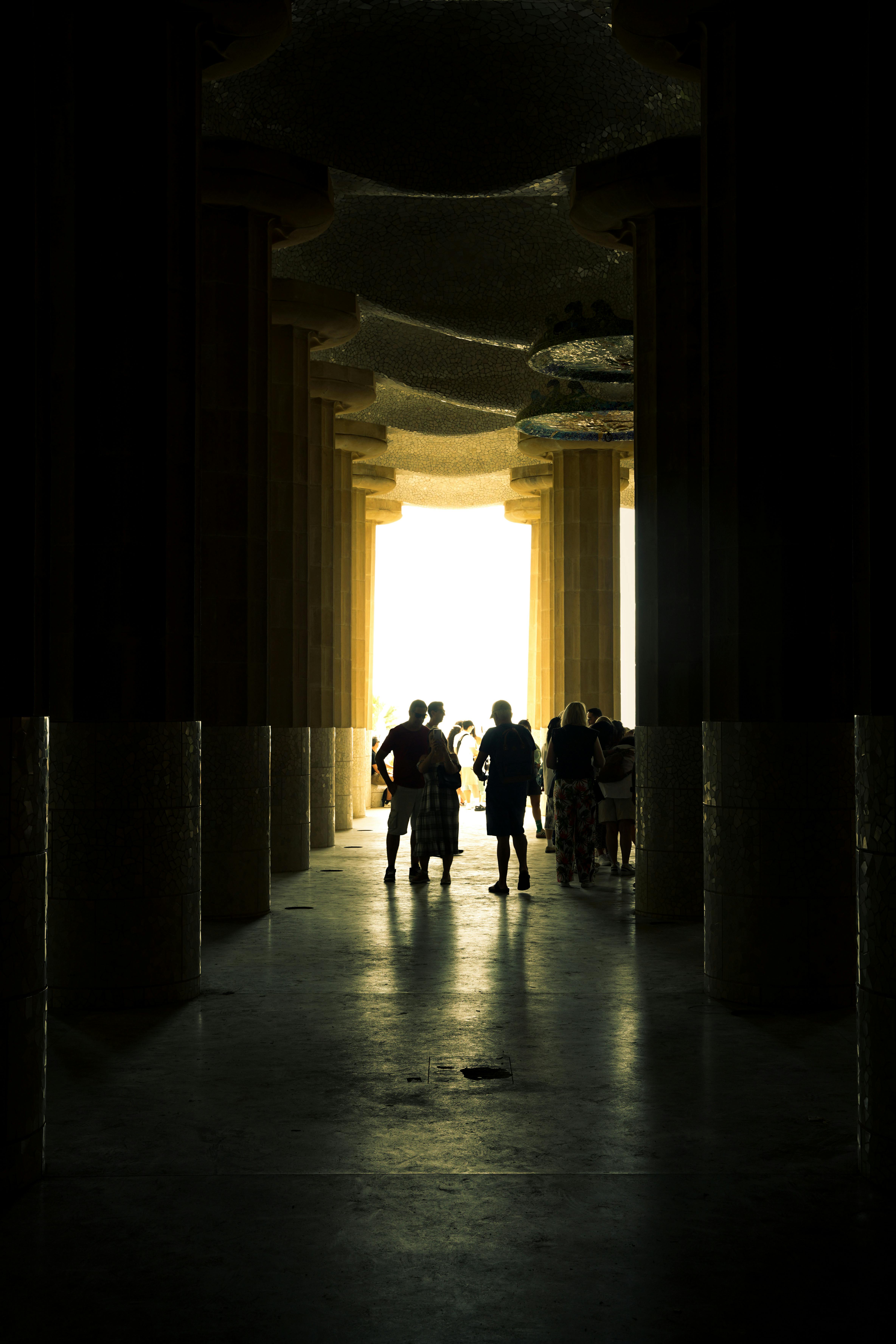 Silhouetted figures walking through the columns of Park Güell in Barcelona.