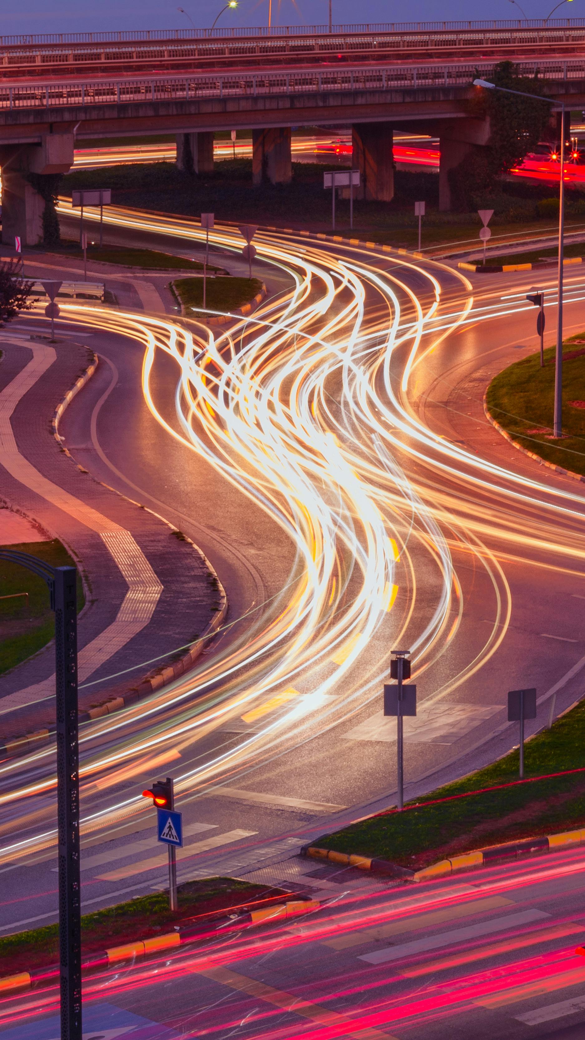 A vibrant long exposure photo capturing light trails at an urban intersection during nighttime.