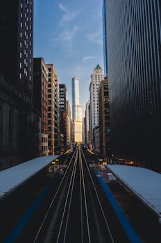 Chicagoland urban scene with train tracks leading to skyscrapers at dusk.